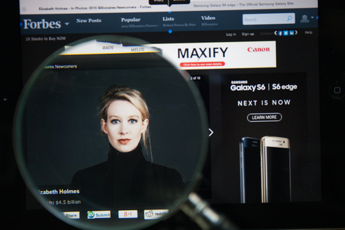 CHIANGMAI, THAILAND - April 30, 2015: Photo of Forbes article page about Elizabeth Holmes on a ipad monitor screen through a magnifying glass. Credit: GongTo/Shutterstock