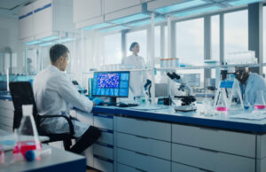 Medical Science Laboratory with Diverse Multi-Ethnic Team of Biotechnology Scientists Developing Drugs, Microbiologist Working on Computer with Display Showing Gene Editing Interface.