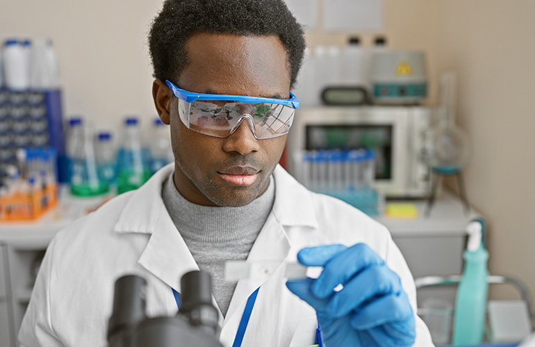 African american male scientist analyzing a specimen in a laboratory setting, portraying research and healthcare.